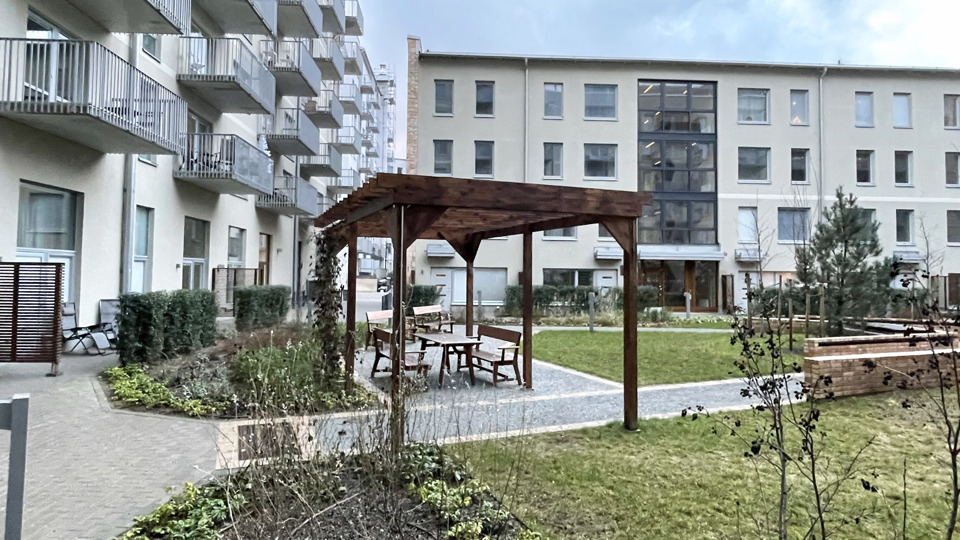 Gemensam innergård med träpaviljong och och sittmöbler.