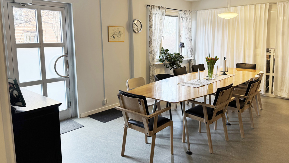 Ljust rum med ett långbord och stolar.