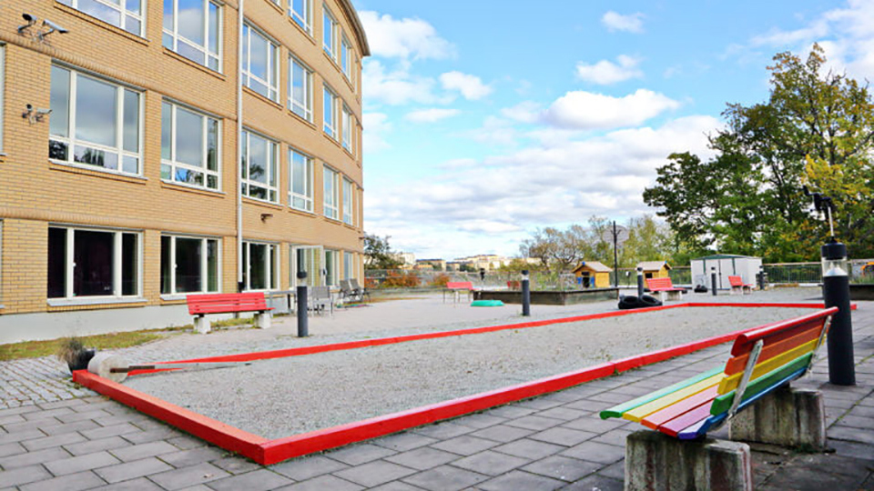 Park med boulebana, bänkar och lekhus.