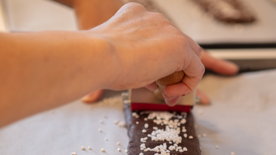 En person bakar chokladkakor med pärlsocker på.