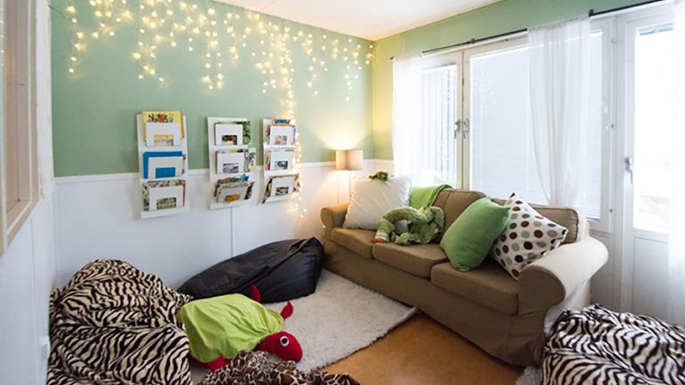 Ett rum med en soffa, kuddar, tidningar och ljus.
