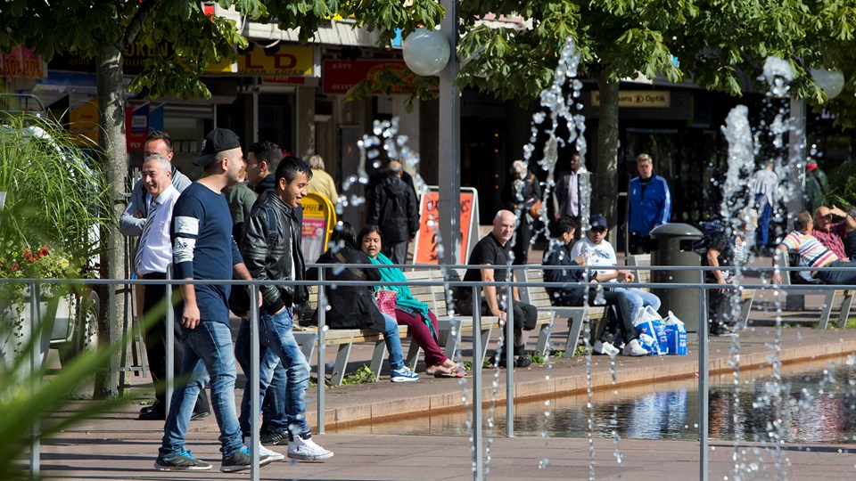 Skärholmens torg en solig sommardag med massa folk som sitter runt fontänen