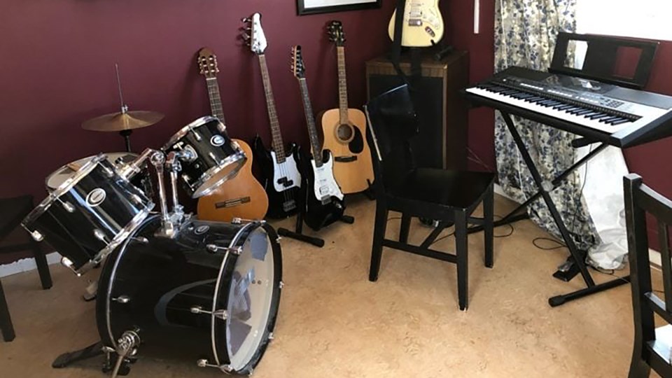 Ett rum med många musikinstrument, till exempel gitarrer, trummor och keyboard.