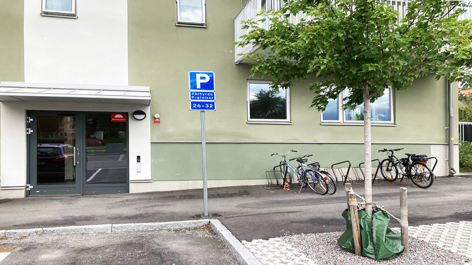 En husfasad och entré. Utanför finns ett litet träd och cyklar står parkerade.